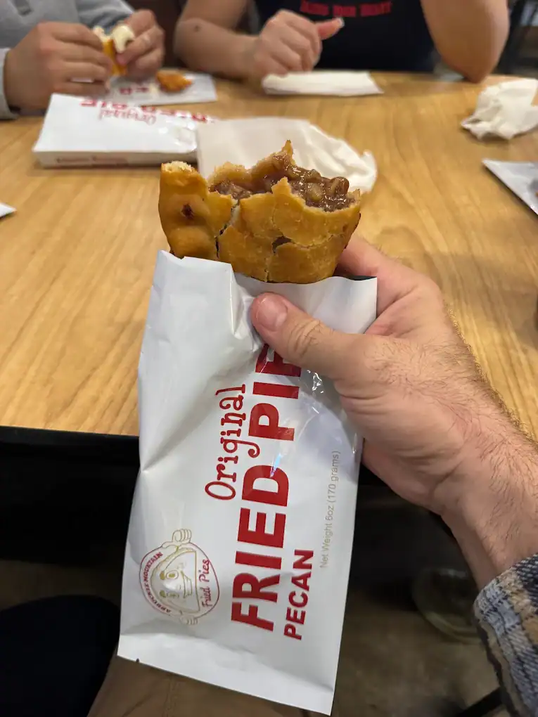 Close-up of a pecan pie in hand at a restaurant table.